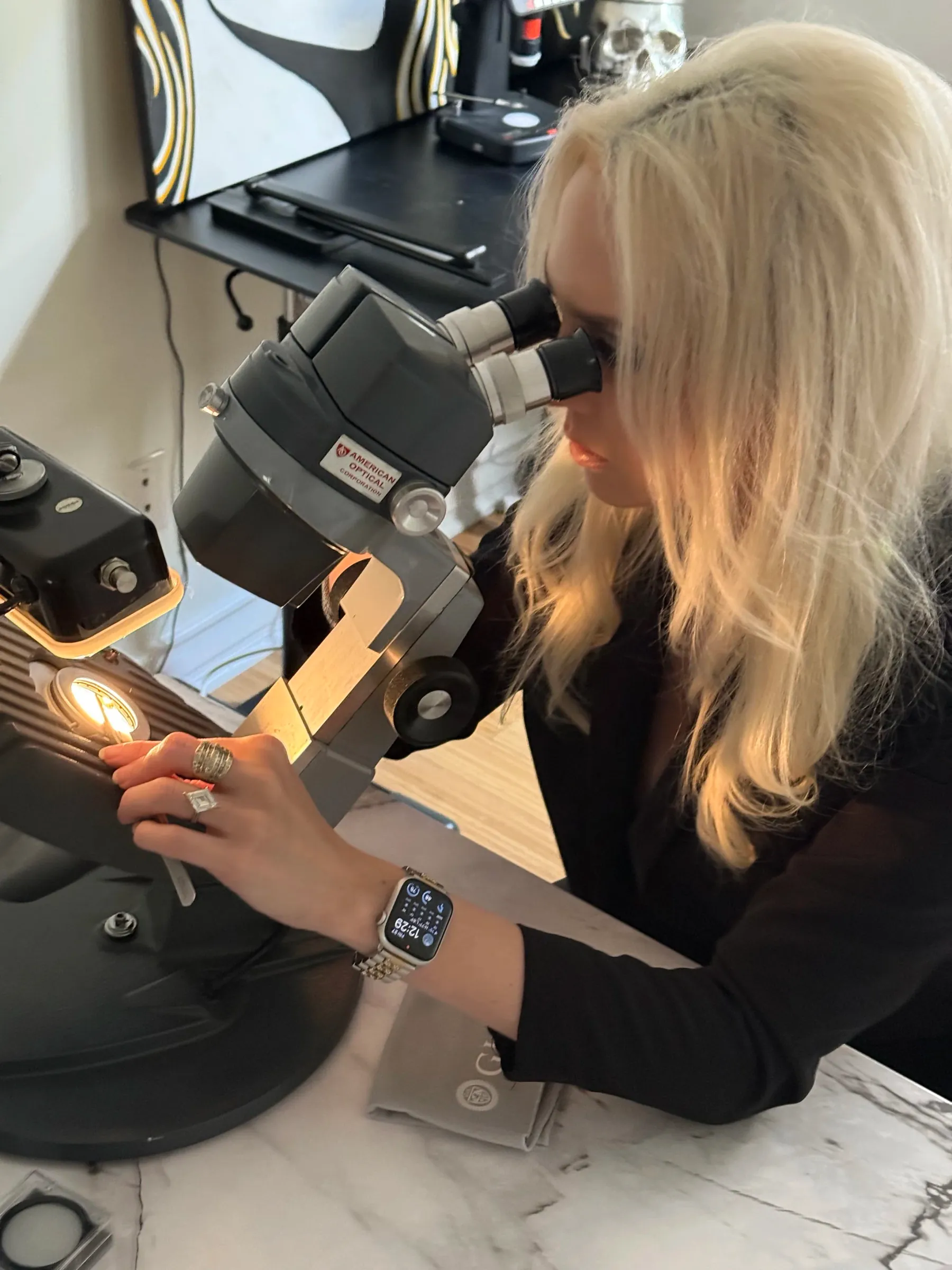 Alexandria Necker, GIA Graduate Gemologist, examining a stone under the microscope at A. D'Mae Diamonds in West Los Angeles