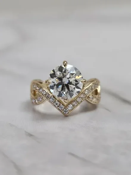 Custom round brilliant diamond engagement ring with an infinity twist band in yellow gold, designed by A. D'Mae Diamonds