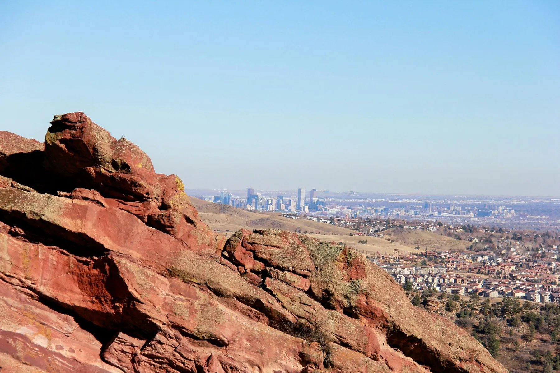 Downtown Denver in the distance beyond red sandstone in the foothills
