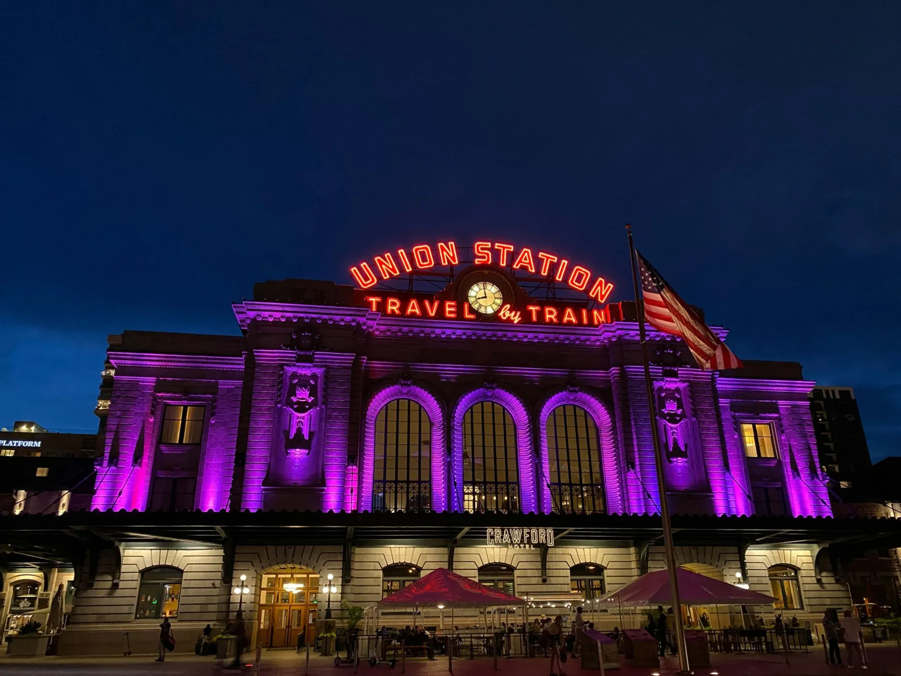Denver Union Station lit up at night under its Travel by Train sign
