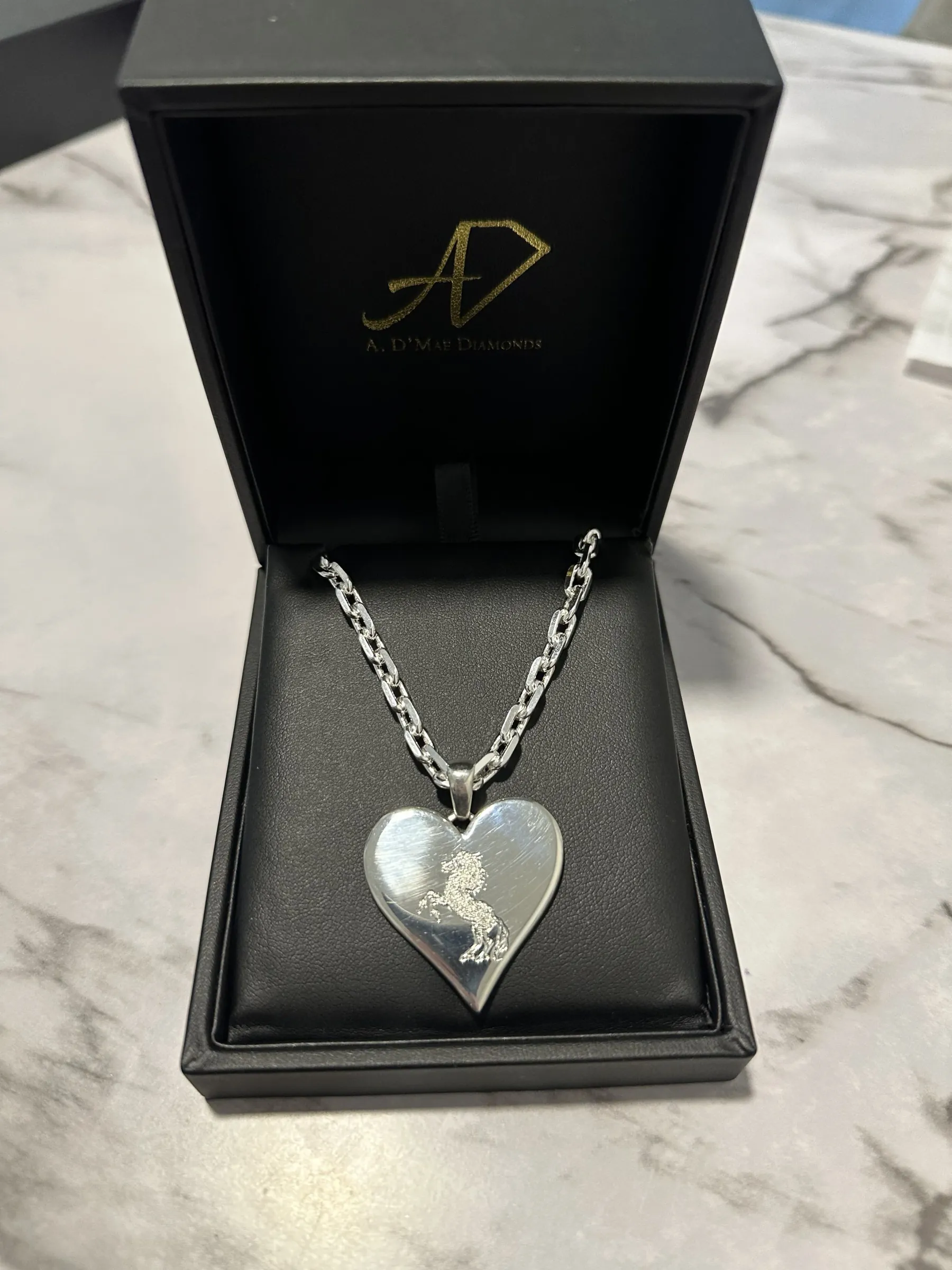 Custom three-dimensional heart necklace with band logo engraving in A. D'Mae Diamonds presentation box, Los Angeles